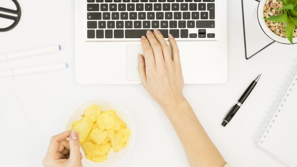 person-typing-while-eating-chips